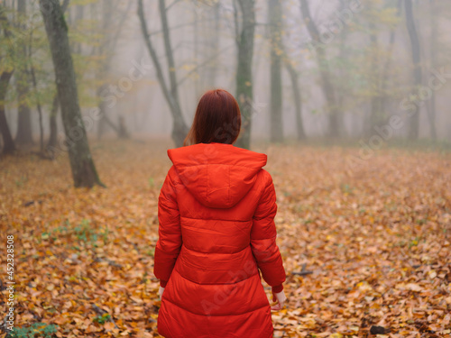 woman in red jacket autumn leaves trees walk fog
