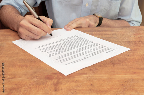 Фотография Person in blue shirt about to sign a contract and accept its clauses
