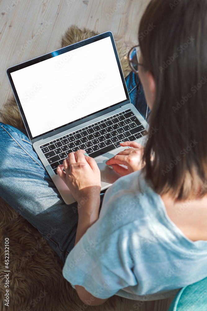 Naklejka premium Young woman using laptop blank screen to work, sitting on the floor at home. Flexible hours and remote work.