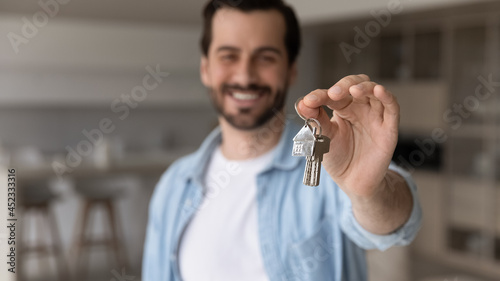 Happy successful male real estate agent offering rent or buying house, flat, apartment, help with mortgage, property deal. Salesman, realtor showing, giving key from new home to buyer, renter, tenant