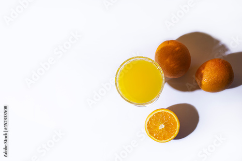 glass with fresh juice and oranges on a light background. Top view, flat lay