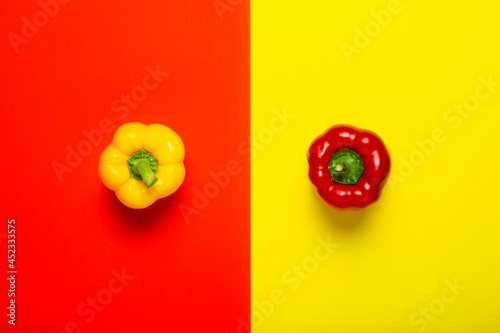 One red and yellow peppers on a yellow-red background. Top view, flat lay photo