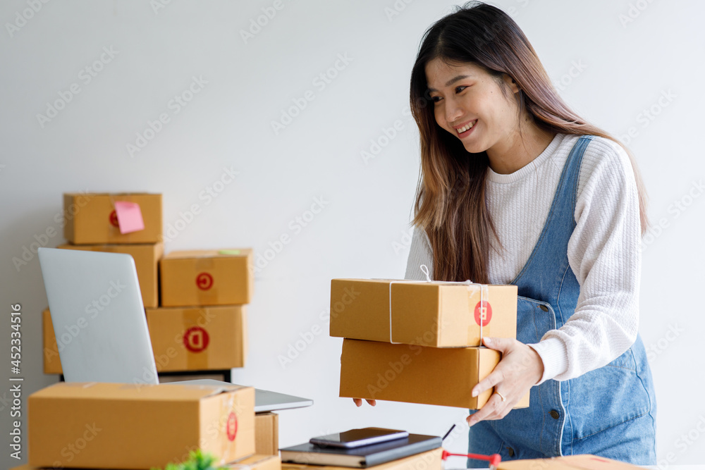 Portrait of Starting Small business entrepreneur SME freelance,Portrait young woman working at home office, BOX,smartphone,laptop, online, marketing, packaging, delivery, SME, e-commerce concept Portrait of Starting Small business entrepreneur SME freelance,Portrait young woman working at home office, BOX,smartphone,laptop, online, marketing, packaging, delivery, SME, e-commerce concept
