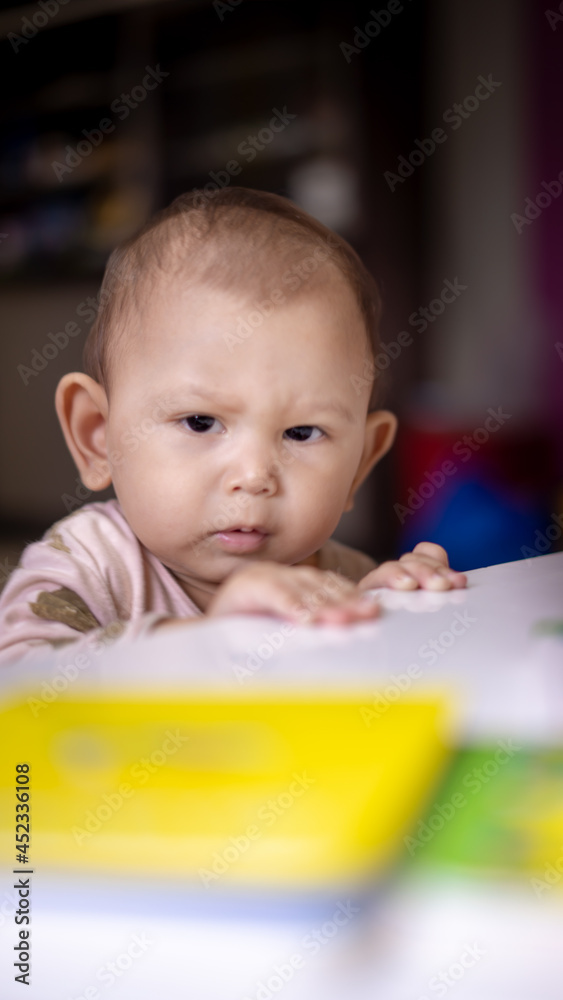 Baby Asian Girl peaking over table as she practices to stand devloping motor skills Baby Asian Girl peaking over table as she practices to stand devloping motor skills