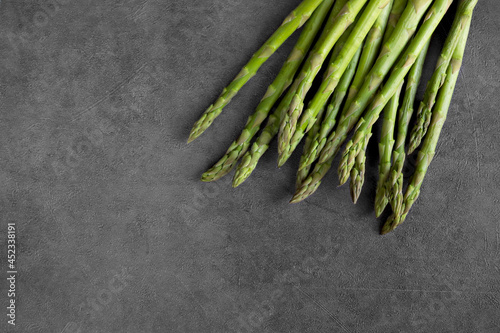 Young green asparagus on a dark concrete background. Vegetables. Vegetarian food. Shoots, asparagus sprouts. Healthy food. The concept of cooking. Food background.