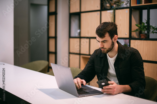 A man works on a laptop in an office or coworking