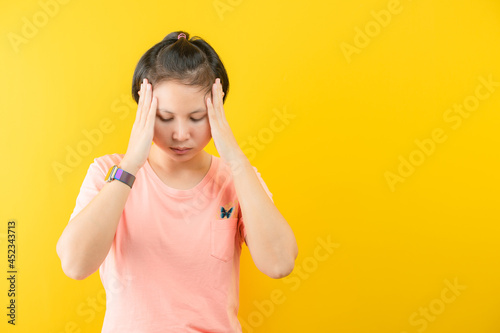 Portrait of beautiful young short hair with  touching her temples feeling stress, on yellow background photo