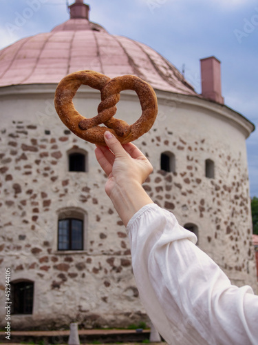 Vyborg pretzel in hand against the background of the old round tower (Symbol of Vyborg) photo