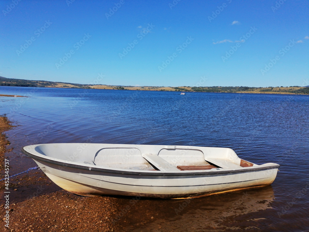Fishing boat on a wonderful blue lake on the mountain. Beautiful landscape, in the background hills, forest and sky. Serbia, Vlasina Lake. Fishing boat on a wonderful blue lake on the mountain. Beautiful landscape, in the background hills, forest and sky. Serbia, Vlasina Lake.