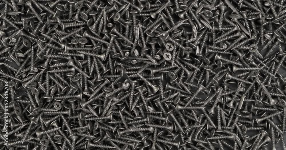 Rotating a bunch of black screws. Industrial background. Rotating a bunch of black screws. Industrial background.