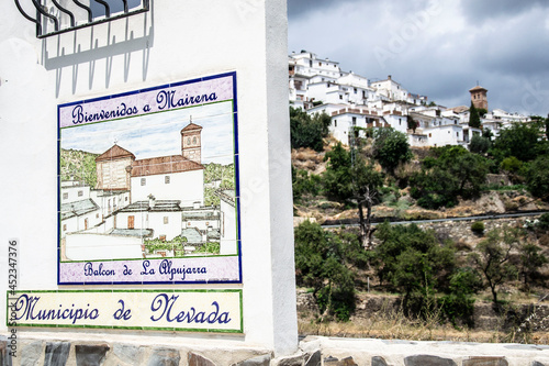 sign indicating the town of the Alpujarra that reads Welcome to Mairena Balcony of the Alpujarra Municipality of Nevada, as well as the view of said town in the background
