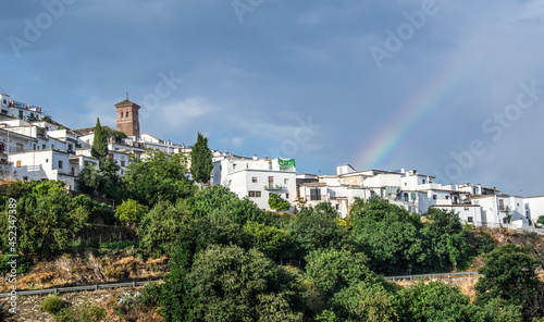 panorama of the town of Mairena of the Alpujarra with white houses, church tower, lots of vegetation and a rainbow photo