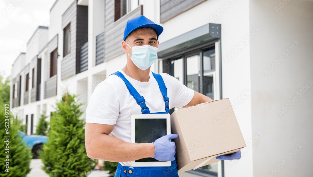 Young courier wearing a protective mask and gloves delivers goods during quarantine Young courier wearing a protective mask and gloves delivers goods during quarantine