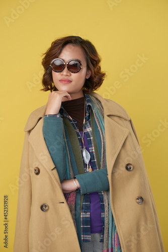 Tableau sur toile Attractive smiling young woman in stylish clothes and sunglasses posing against