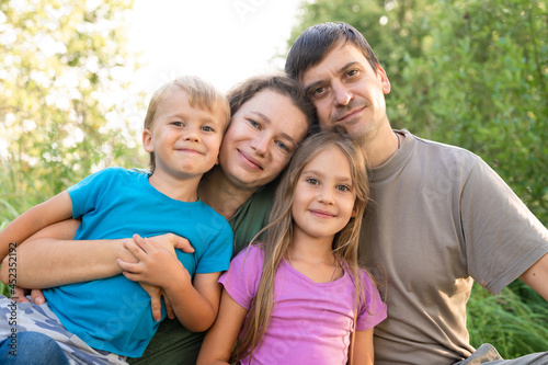 portrait of a happy family, mother and father, son and daughter, in nature outdoor in summer