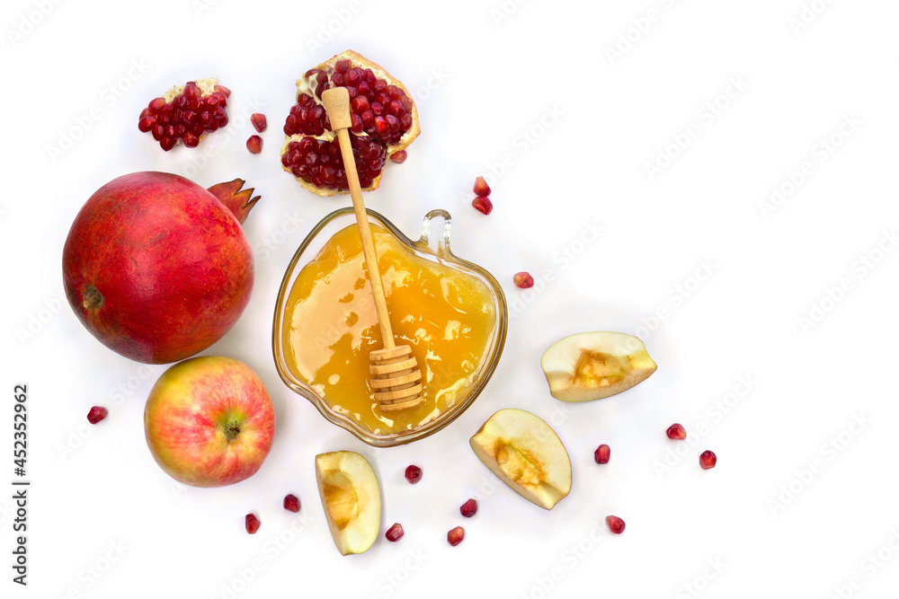 Honey in glass bowl, red apples, garnets, wooden honey dipper on a white background with space for text. Top view, flat lay