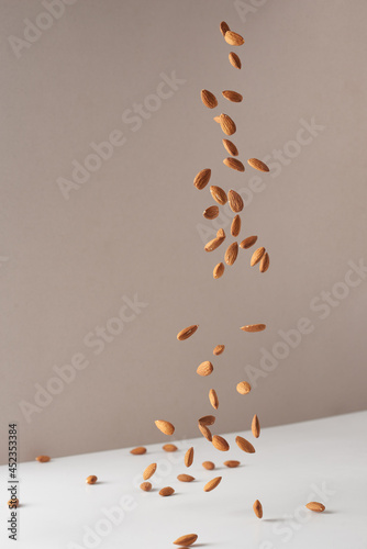 Fotobehang Flying almond nuts. Fresh raw almonds fall on a white background.
