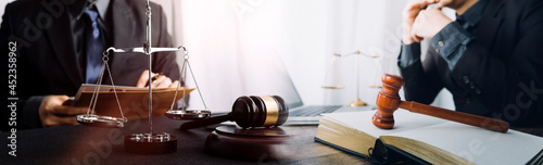 Business and lawyers discussing contract papers with brass scale on desk in office. Law, legal services, advice, justice and law concept picture with film grain effect