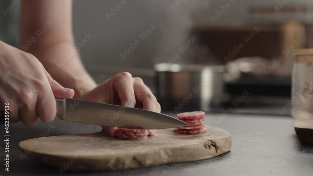Slow motion man slicing salami on olive board Slow motion man slicing salami on olive board