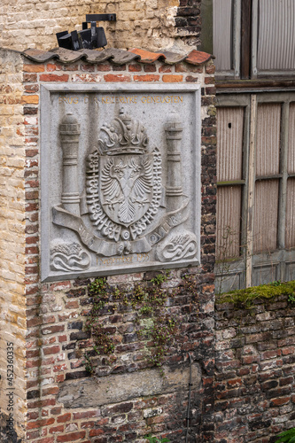 Gent, Flanders, Belgium - July 30, 2021: Closeup of gray stone Emperor Charles V Coat of Arms set in red brick wall at Brug der Keizerlijke Geneugten (Bridge of the emperors pleasures) photo