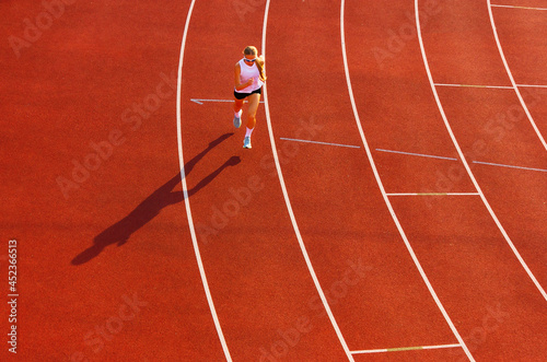 young woman in sports uniform runs along the track of the stadium. sports training and exercise. healthy lifestyle