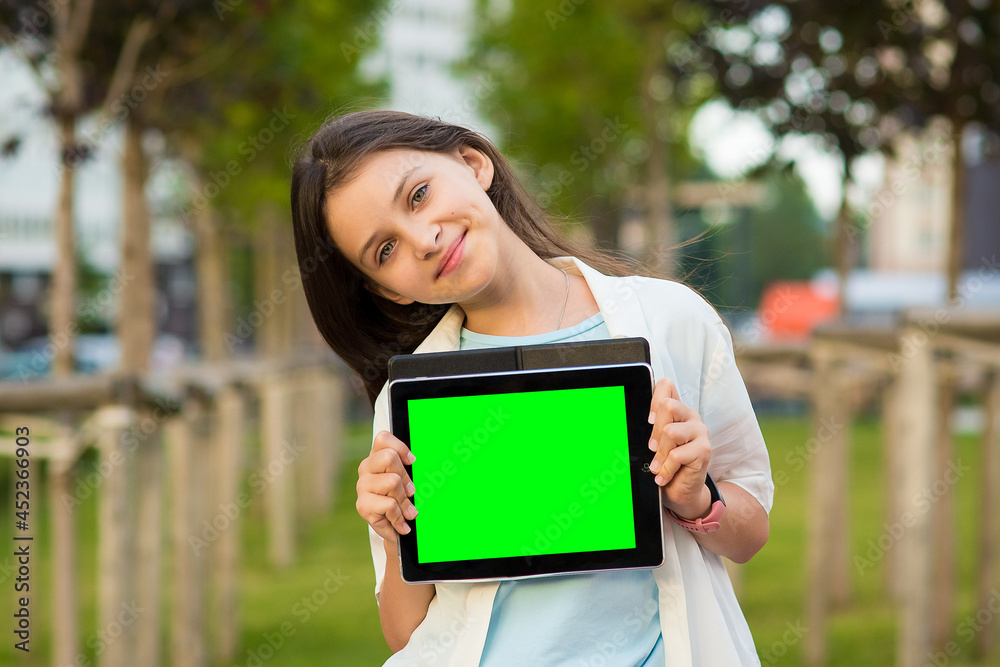 a girl is holding a tablet empty screen in her hands outdoor a girl is holding a tablet empty screen in her hands outdoor