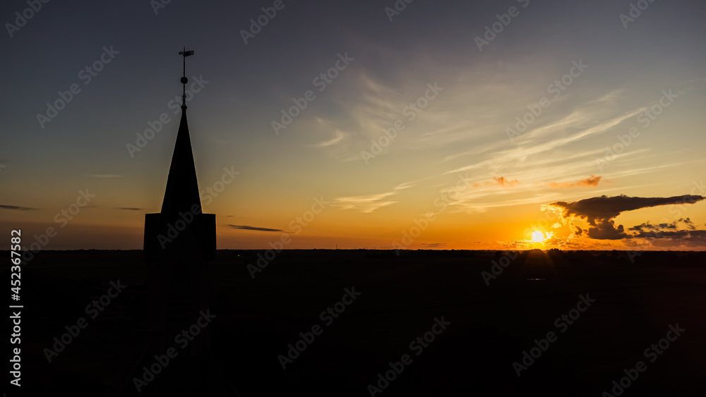 Kirche und Kirchturm im Sonnenuntergang mit weiter Landschaft und Natur im Hintergrund