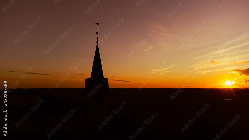 Kirche und Kirchturm im Sonnenuntergang mit weiter Landschaft und Natur im Hintergrund Kirche und Kirchturm im Sonnenuntergang mit weiter Landschaft und Natur im Hintergrund