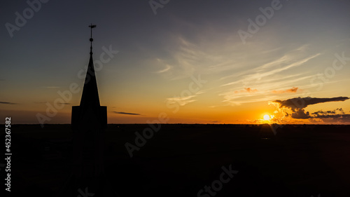 Kirche und Kirchturm im Sonnenuntergang mit weiter Landschaft und Natur im Hintergrund © Noah