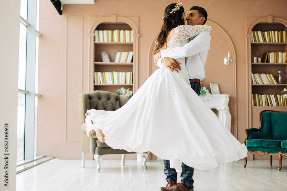 Naklejka premium Happy wedding couple, attractive bride and groom hug each other, the groom hugs and holds the bride in his arms and circles her