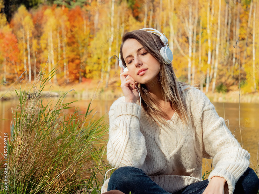 woman with headphones near lake in autumn time woman with headphones near lake in autumn time