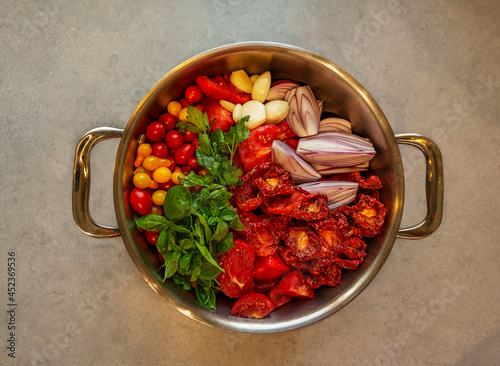 Ein Kochtopf mit frischen Tomaten und Gewürzen von oben.