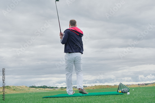 a man plays golf on a green background © madnessbrains