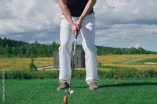 legs of a man with a golf club playing