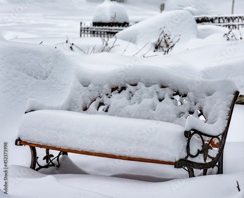 A bench in the snow at the Nikolskoye cemetery in St. Petersburg. photo