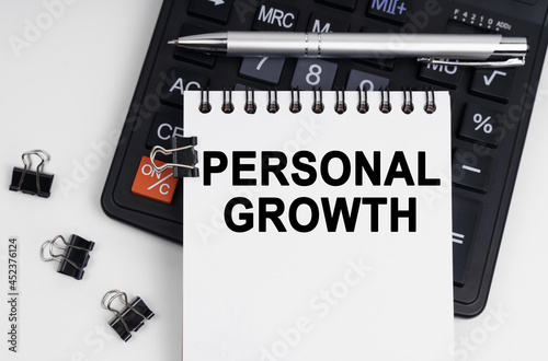 On the table is a calculator, a pen and a notebook with the inscription - PERSONAL GROWTH