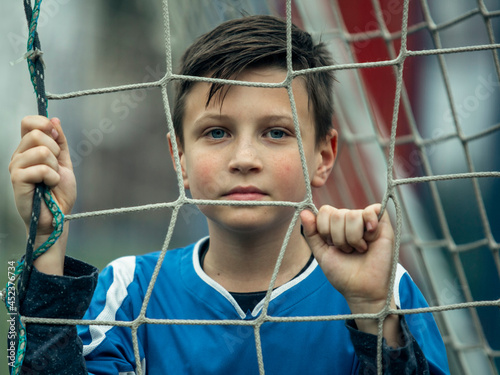 A teen boy portrait near the gate on the football field.