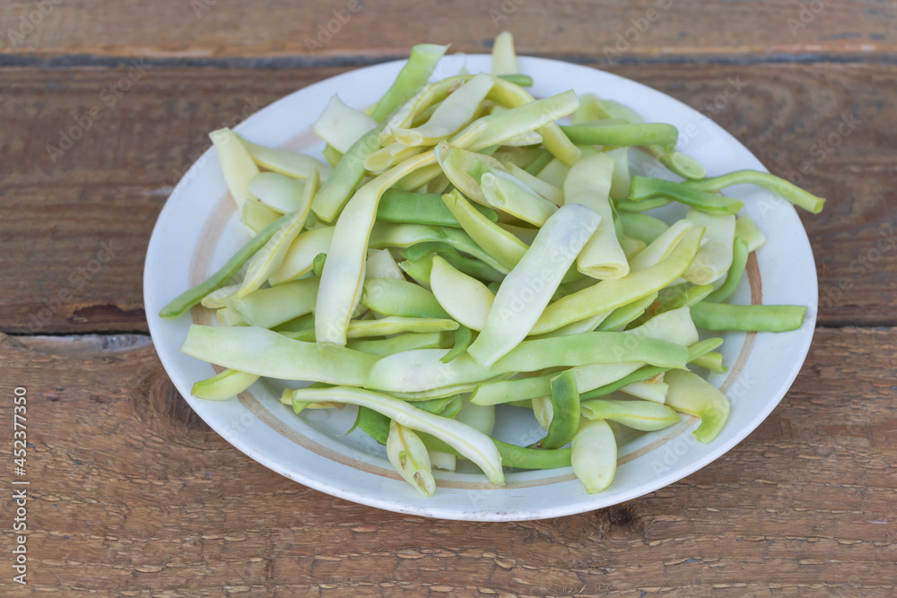 Green beans in a plate ready for cooking - Wooden background Green beans in a plate ready for cooking - Wooden background