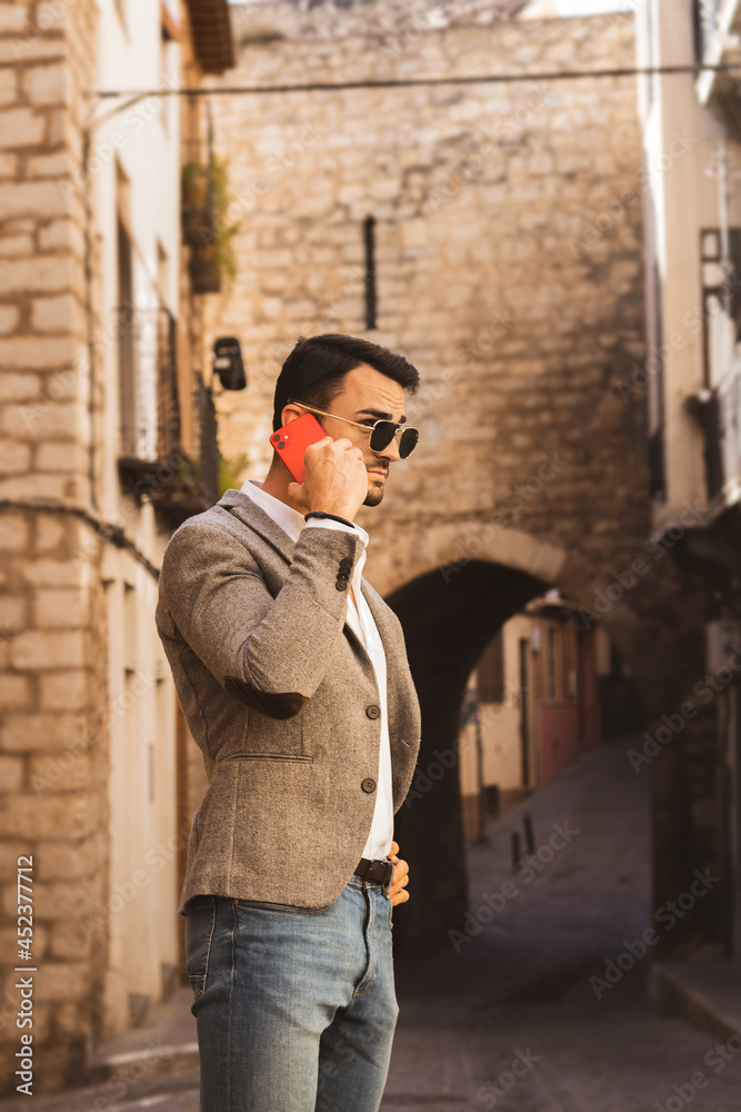
young businessman talking on the cell phone in the middle of an urban street in Andalusia.