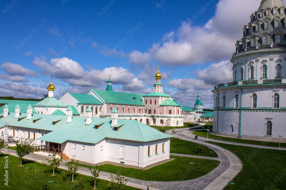 architectural ensemble with the white-stone religious architecture of the New Jerusalem on a sunny bright day and a dramatic blue sky with clouds in Istra Russia