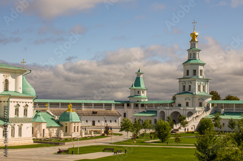 historical white-stone architecture of the New Jerusalem Monastery against the background of a dramatic blue sky with white clouds on a sunny summer day in Istra Moscow Region