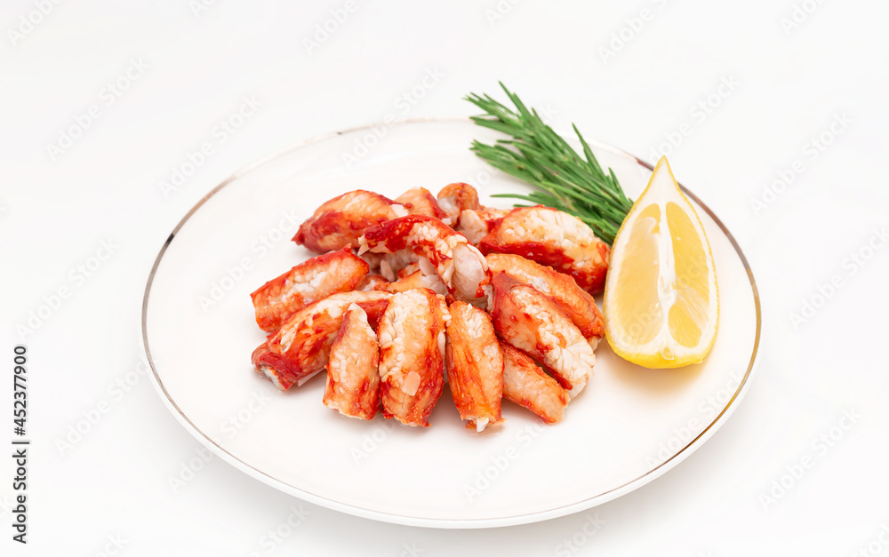 Seafood salad with crab meat and fresh romaine lettuce leaves, rosemary and lemon on a white plate Seafood salad with crab meat and fresh romaine lettuce leaves, rosemary and lemon on a white plate