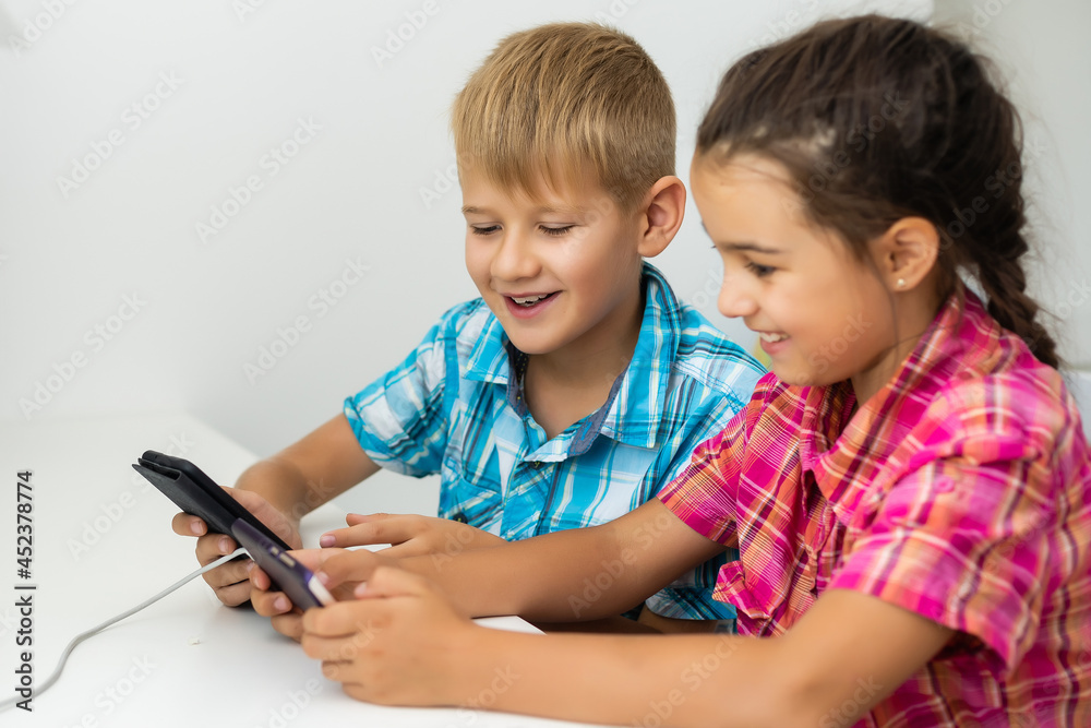 boy playing with smartphone next to his sister in the room at home. boy playing with smartphone next to his sister in the room at home.