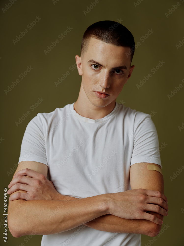 a guy with an adhesive plaster on his shoulder crossed his arms over his chest on a dark background vaccine passport a guy with an adhesive plaster on his shoulder crossed his arms over his chest on a dark background vaccine passport