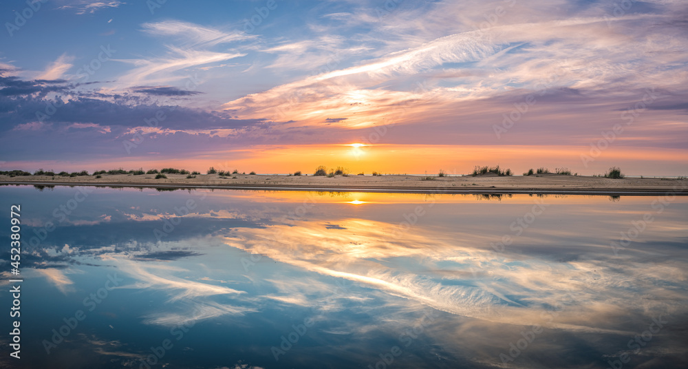 Obraz premium Colorful sunset over the Baltic sea from the pine forest viewpoint. Cloud reflections in calm water.