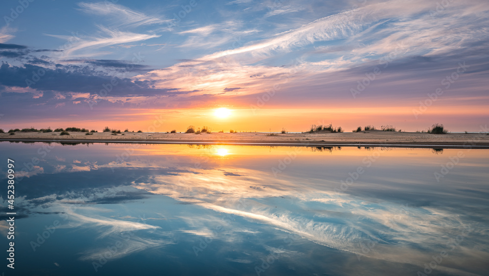 Obraz premium Colorful sunset over the Baltic sea from the pine forest viewpoint. Cloud reflections in calm water.