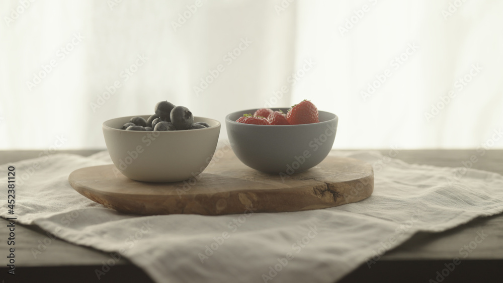 fresh blueberries and strawberries in ceramic bowls with natural light fresh blueberries and strawberries in ceramic bowls with natural light
