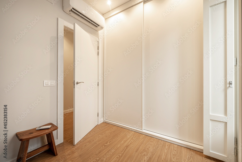 Fototapeta premium White fitted wardrobe with sliding doors with air conditioning in a bedroom of a vacation rental apartment