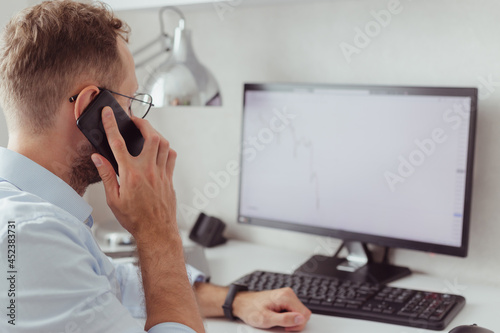 Young businessman brocker on mobile phone in office. Investment, trading stock on bear market photo