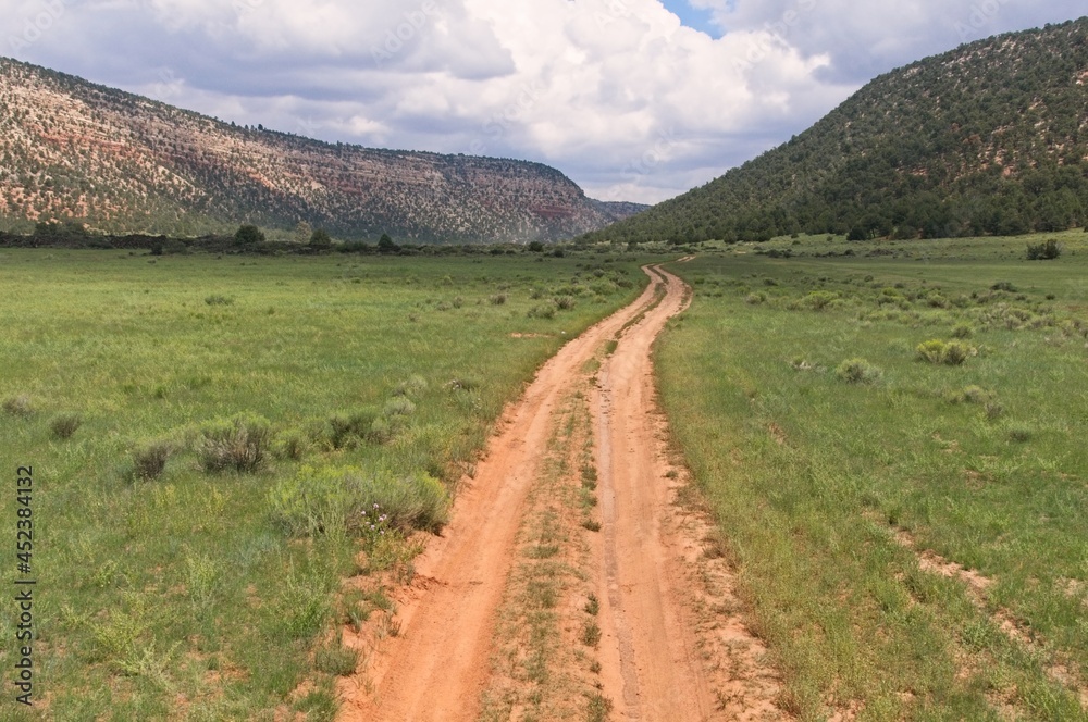 A dirt road runs through a New Mexico valley flanked by scrub covered mountains.